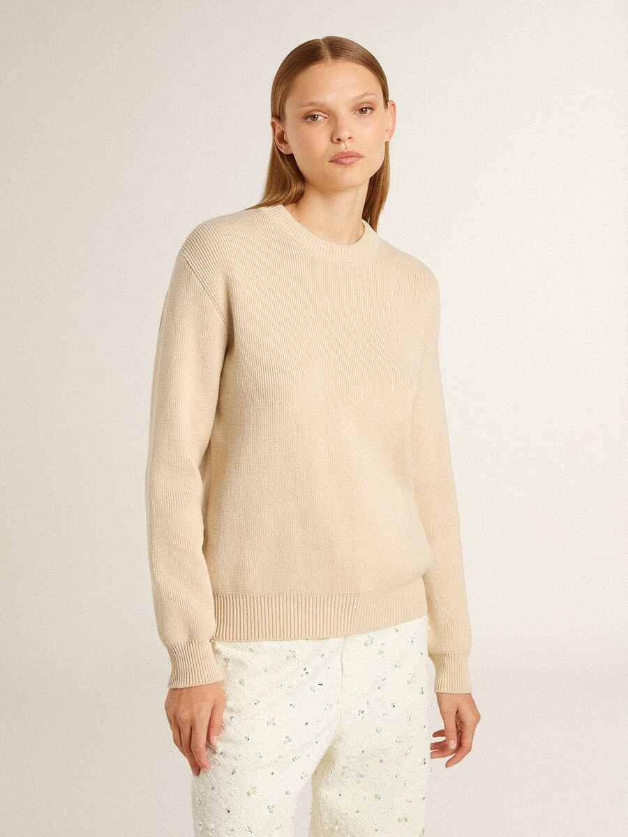 beige damestrui met golden-letters op de achterkant.
