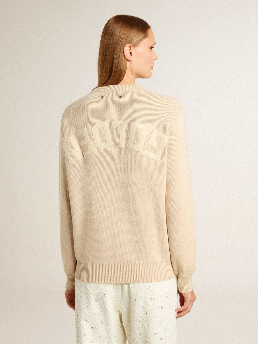beige damestrui met golden-letters op de achterkant.