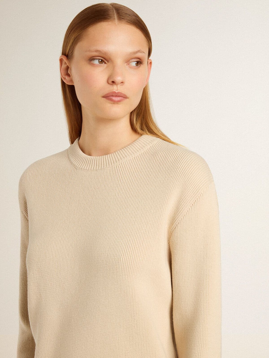 beige damestrui met golden-letters op de achterkant.