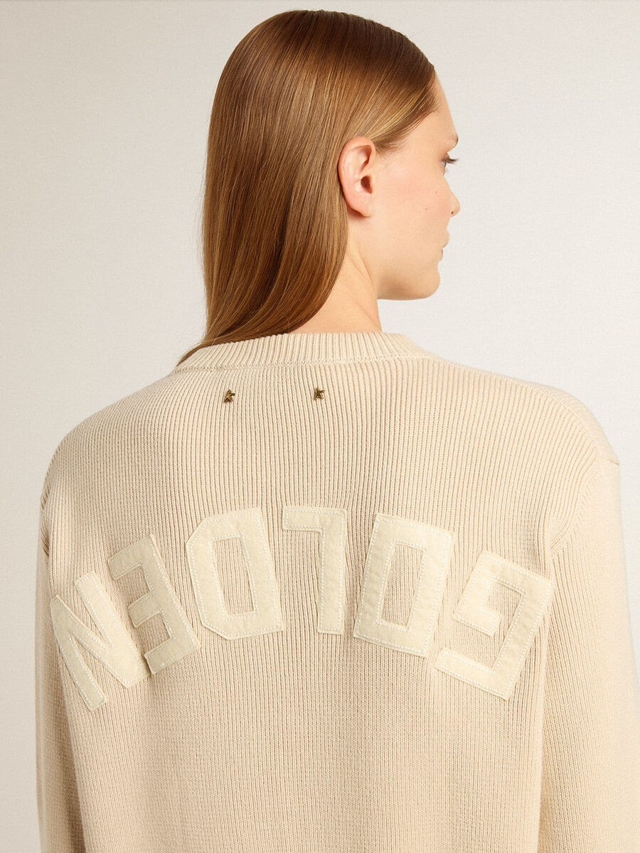 beige damestrui met golden-letters op de achterkant.