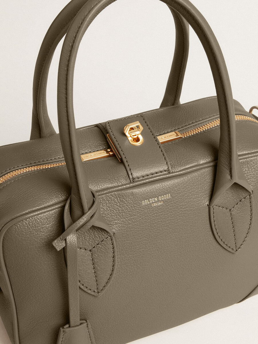 vita-tas van saliegroen leer met gouden details.